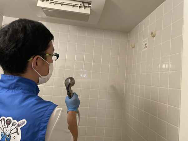 浴室の壁に水をかける作業員
