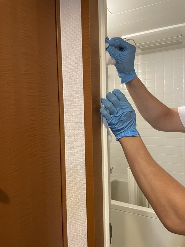 浴室の扉のパッキンを掃除する作業員