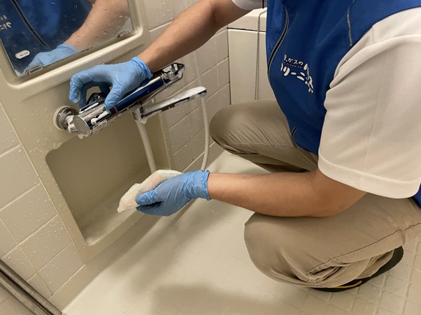浴室の水栓を掃除する作業員